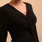 model is wearing diva catwalk gately pencil dress with long sleeves and twisted low v-neck in black front close up