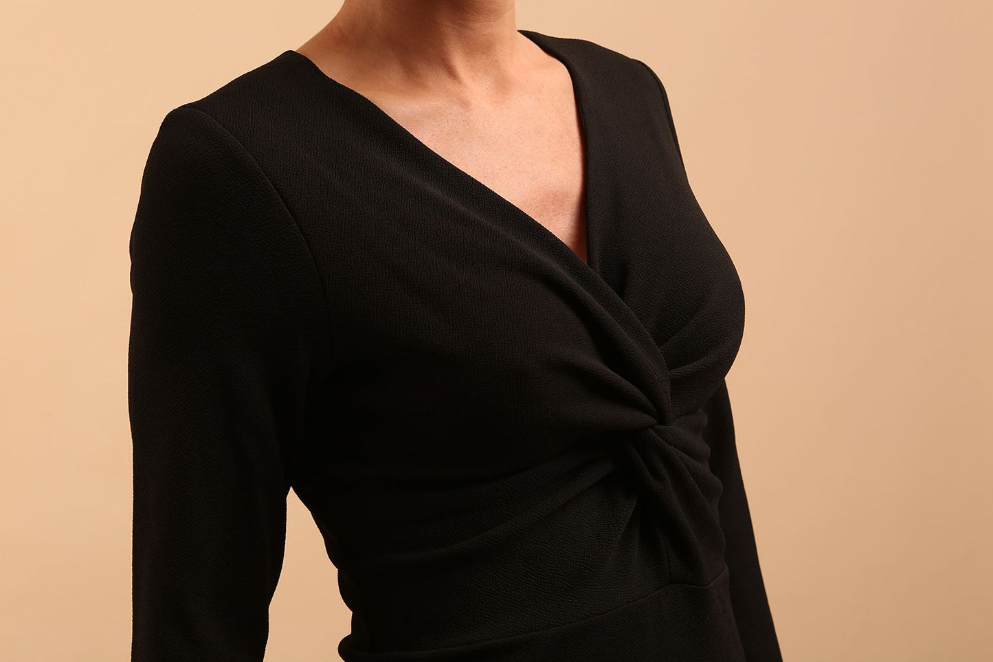 model is wearing diva catwalk gately pencil dress with long sleeves and twisted low v-neck in black front close up