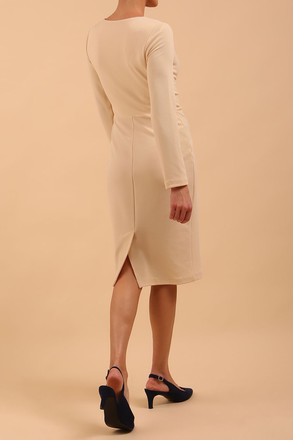 model is wearing diva catwalk gately pencil dress with long sleeves and twisted low v-neck in sandshell beige back