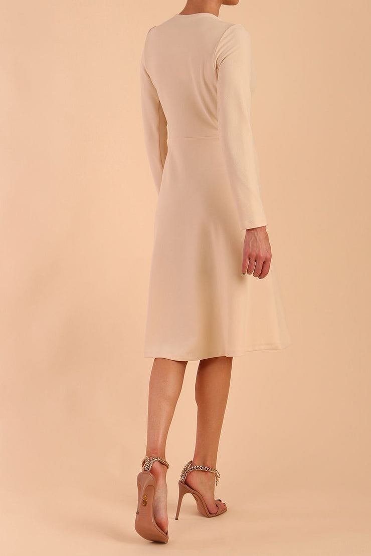 model is wearing diva catwalk moraig swing long sleeve dress with high cowl neckline and wrap skirt in beige side back