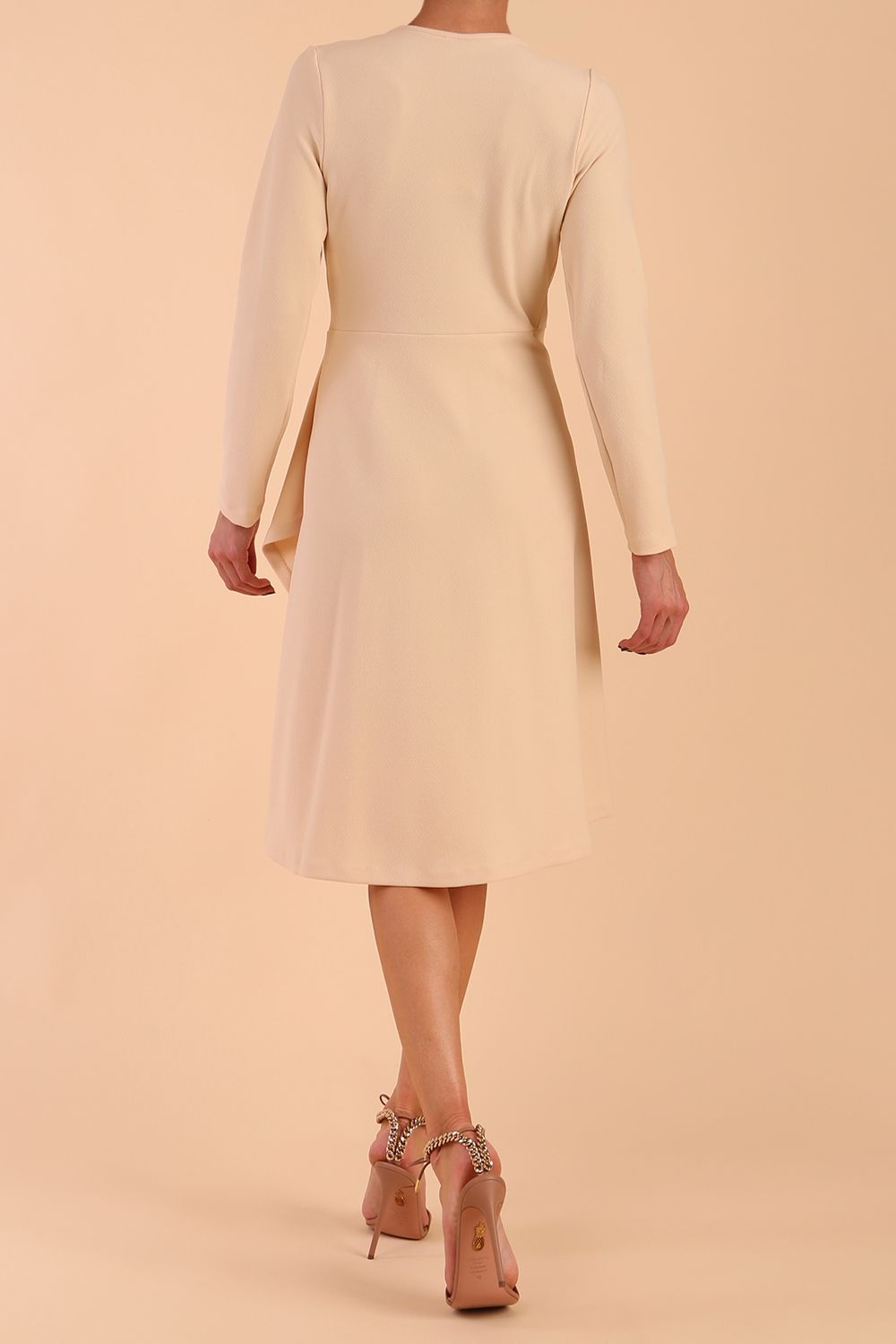 model is wearing diva catwalk moraig swing long sleeve dress with high cowl neckline and wrap skirt in beige back