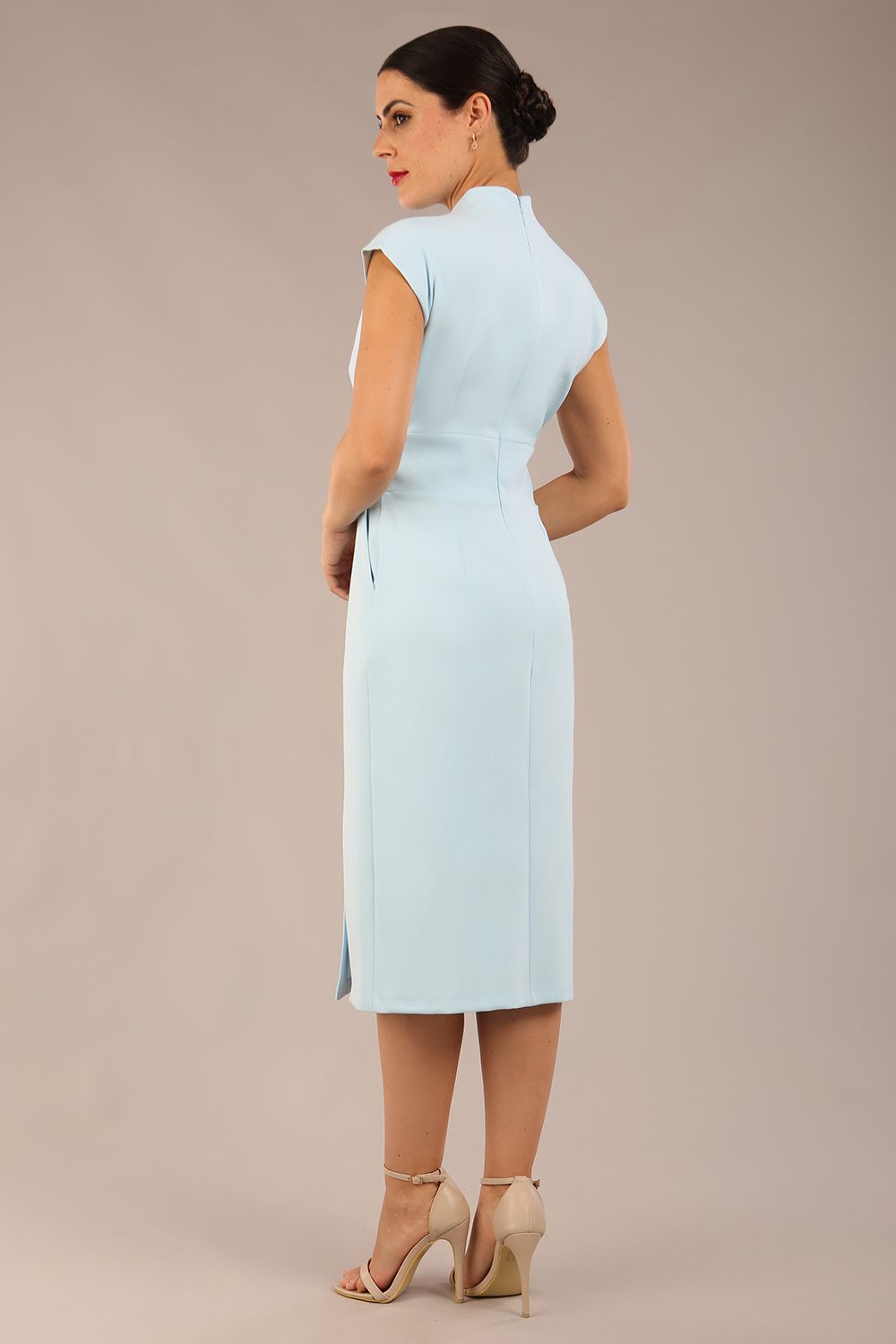 brunette Model is wearing a diva catwalk Derby pencil skirt dress cap sleeves with buttons details at the waistband and star neckline below the knee length with pockets in sky blue colour back image with sunglasses