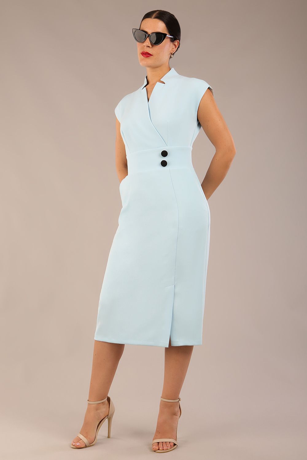 brunette Model is wearing a diva catwalk Derby pencil skirt dress cap sleeves with buttons details at the waistband and star neckline below the knee length with pockets in sky blue colour front image with sunglasses