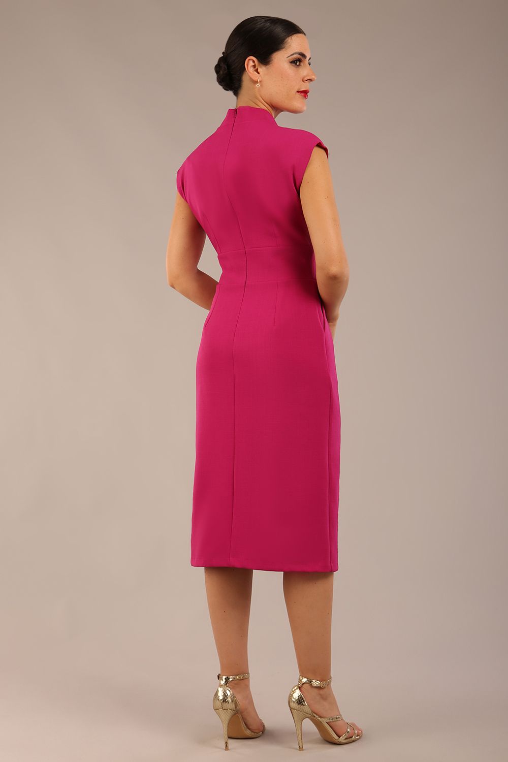 brunette Model is wearing a diva catwalk Derby pencil skirt dress cap sleeves with buttons details at the waistband and star neckline below the knee length with pockets in magenta colour back image 