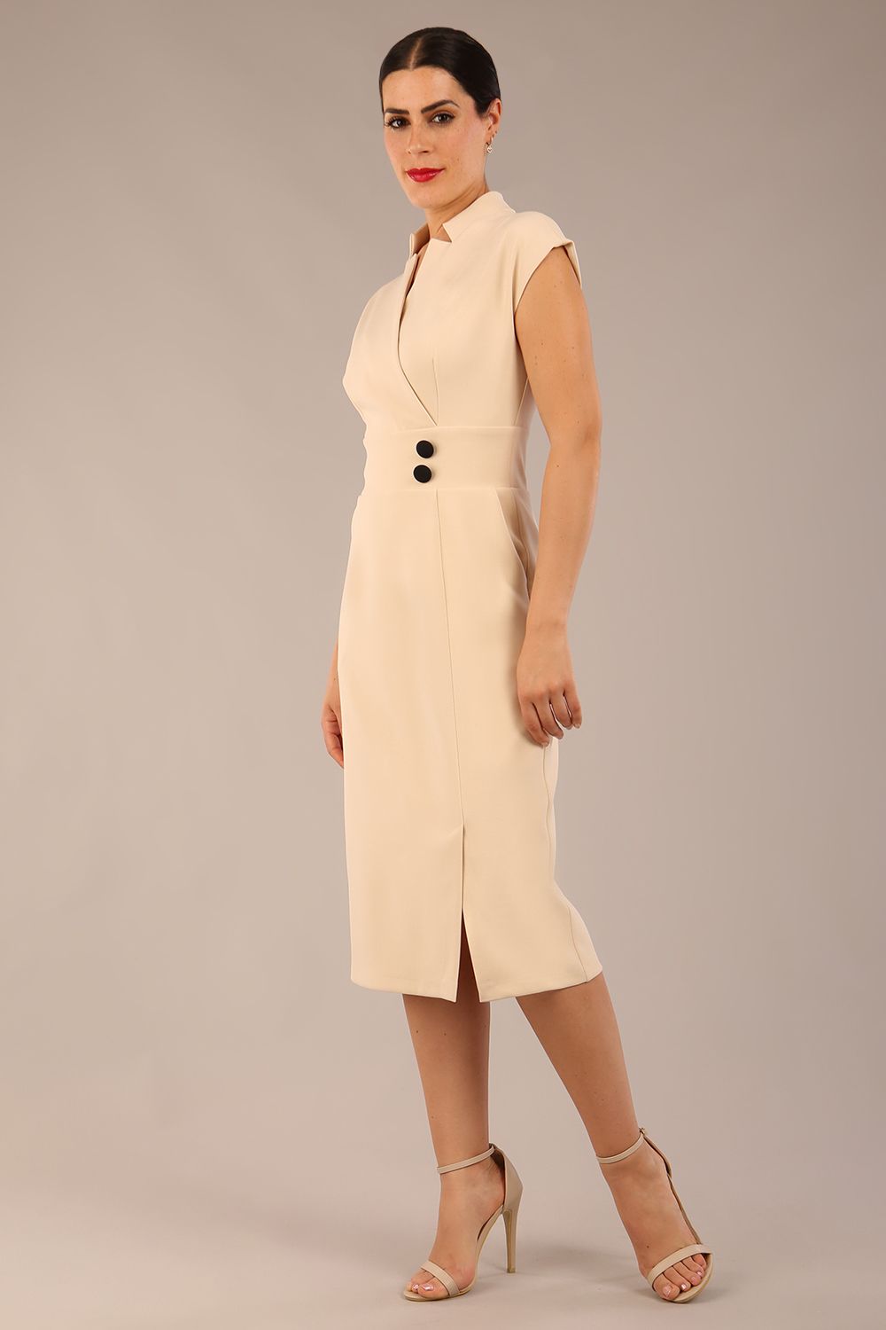 brunette Model is wearing a diva catwalk Derby pencil skirt dress cap sleeves with buttons details at the waistband and star neckline below the knee length with pockets in sandshell beige colour front image 