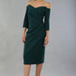 model is wearing diva catwalk lauren odd shoulder asymmetric neckline pencil dress with sleeves in forest green front