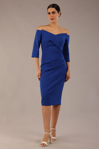 brunette model is wearing a diva catwalk lauren off shoulder asymmetric neckline pencil dress with sleeves in cobalt blue front 