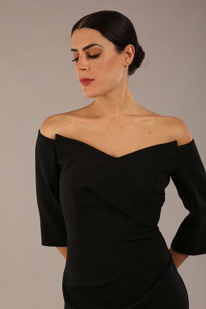 brunette model is wearing a diva catwalk lauren off shoulder asymmetric neckline pencil dress with sleeves in black front close up
