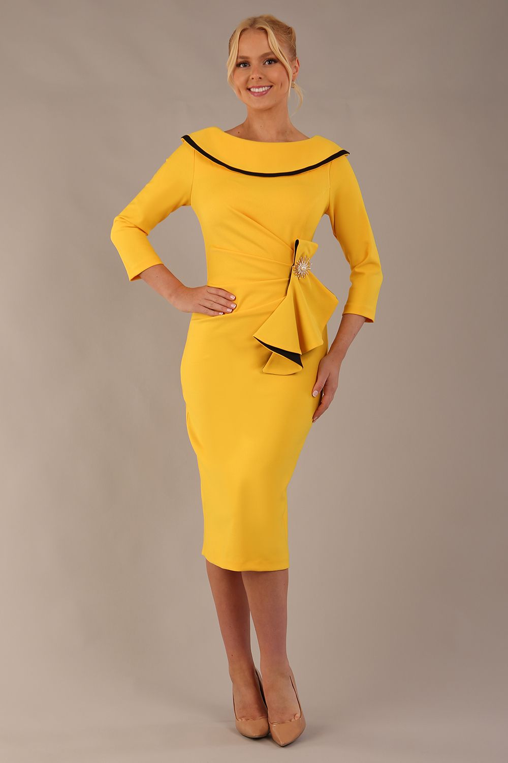 Model wearing diva catwalk Seed Elsye 3/4 Sleeve Knee Length Pencil Dress with Fold over bateau collar neckline with contrast piping and Bow feature on the left side of the bodice with decorative brooch in Daffodil Yellow colour front (Daffodil Yellow / Black Contrast)