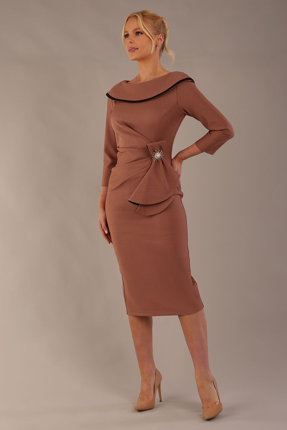 Model wearing diva catwalk Seed  Elsye 3/4 Sleeve Knee Length Pencil Dress with Fold over bateau collar neckline with contrast piping and Bow feature on the left side of the bodice with decorative brooch in Acorn Brown colour front (Acorn Brown / Black Contrast)