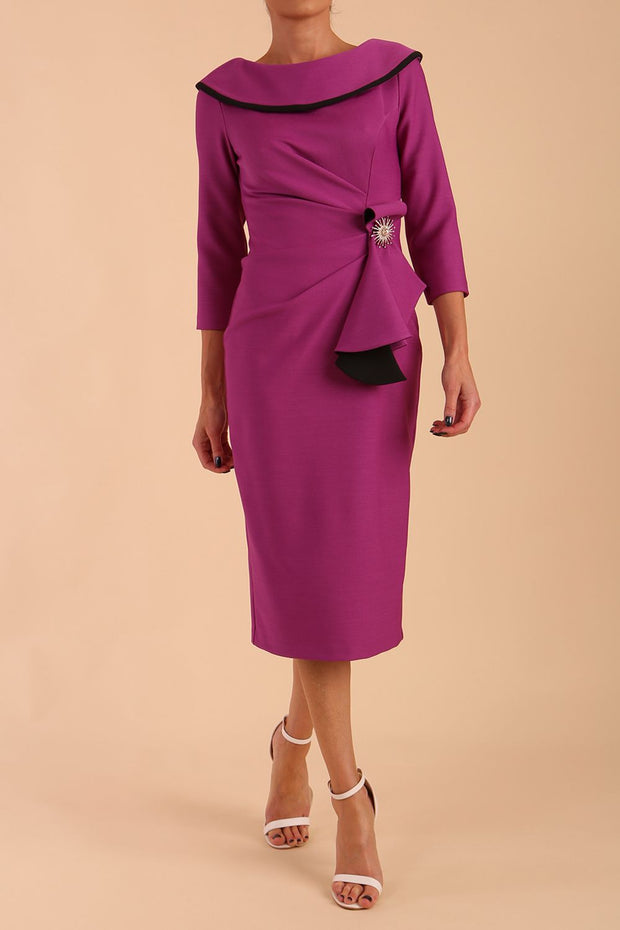 Model wearing diva catwalk Seed Elsye 3/4 Sleeve Knee Length Pencil Dress with Fold over bateau collar neckline with contrast piping and Bow feature on the left side of the bodice with decorative brooch in Dawn Purple colour front