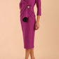Model wearing diva catwalk Seed Elsye 3/4 Sleeve Knee Length Pencil Dress with Fold over bateau collar neckline with contrast piping and Bow feature on the left side of the bodice with decorative brooch in Dawn Purple colour front side