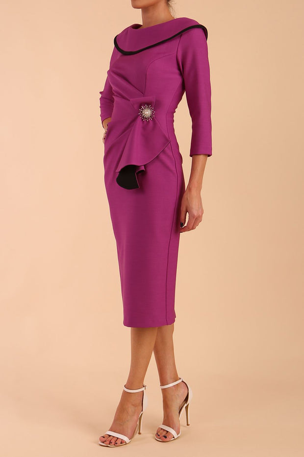 Model wearing diva catwalk Seed Elsye 3/4 Sleeve Knee Length Pencil Dress with Fold over bateau collar neckline with contrast piping and Bow feature on the left side of the bodice with decorative brooch in Dawn Purple colour front side