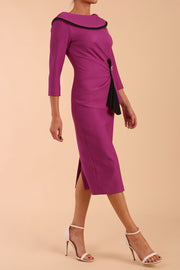 Model wearing diva catwalk Seed Elsye 3/4 Sleeve Knee Length Pencil Dress with Fold over bateau collar neckline with contrast piping and Bow feature on the left side of the bodice with decorative brooch in Dawn Purple colour front side