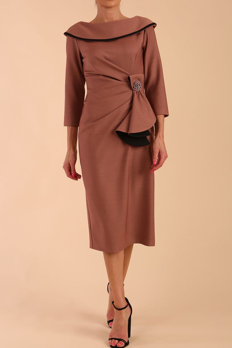 Model wearing diva catwalk Seed  Elsye 3/4 Sleeve Knee Length Pencil Dress with Fold over bateau collar neckline with contrast piping and Bow feature on the left side of the bodice with decorative brooch in Acorn Brown colour front