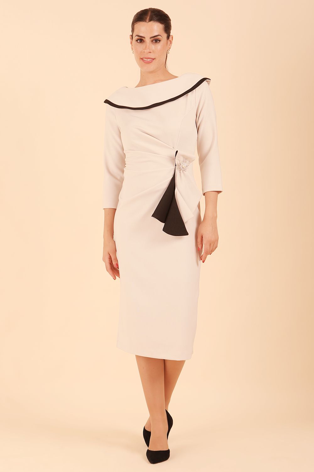 Model wearing diva catwalk Seed Elsye 3/4 Sleeve Knee Length Pencil Dress with Fold over bateau collar neckline with contrast piping and Bow feature on the left side of the bodice in Sandy Cream colour front