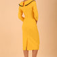 odel wearing diva catwalk Seed Elsye 3/4 Sleeve Knee Length Pencil Dress with Fold over bateau collar neckline with contrast piping and Bow feature on the left side of the bodice with decorative brooch in Daffodil Yellow colour back