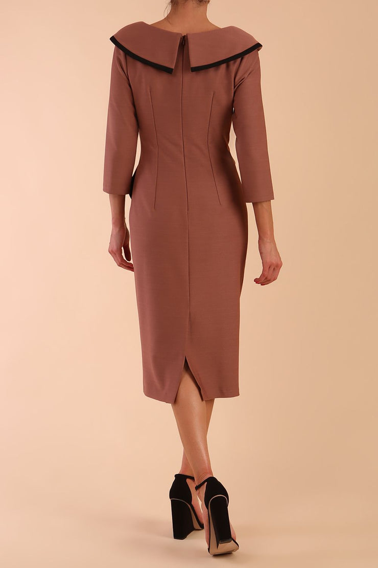 Model wearing diva catwalk Seed  Elsye 3/4 Sleeve Knee Length Pencil Dress with Fold over bateau collar neckline with contrast piping and Bow feature on the left side of the bodice with decorative brooch in Acorn Brown colour back