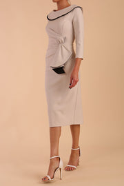 Model wearing diva catwalk Seed  Elsye 3/4 Sleeve Knee Length Pencil Dress with Fold over bateau collar neckline with contrast piping and Bow feature on the left side of the bodice in Sandy Cream colour front side