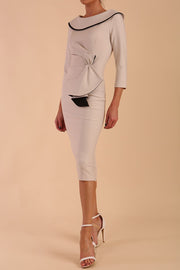 Model wearing diva catwalk Seed  Elsye 3/4 Sleeve Knee Length Pencil Dress with Fold over bateau collar neckline with contrast piping and Bow feature on the left side of the bodice in Sandy Cream colour front side