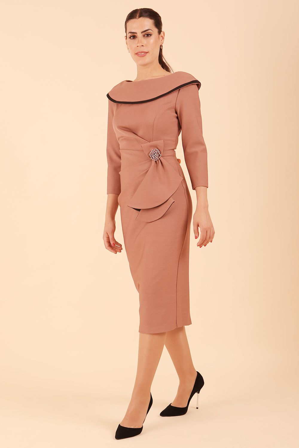 Model wearing diva catwalk Seed Elsye 3/4 Sleeve Knee Length Pencil Dress with Fold over bateau collar neckline with contrast piping and Bow feature on the left side of the bodice with decorative brooch in Acorn Brown colour front