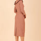 Model wearing diva catwalk Seed Elsye 3/4 Sleeve Knee Length Pencil Dress with Fold over bateau collar neckline with contrast piping and Bow feature on the left side of the bodice with decorative brooch in Acorn Brown colour back side