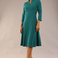 model is wearing diva catwalk palmerston vintage style a-line dress with sleeves and high neck with a slit in pacific green colour front