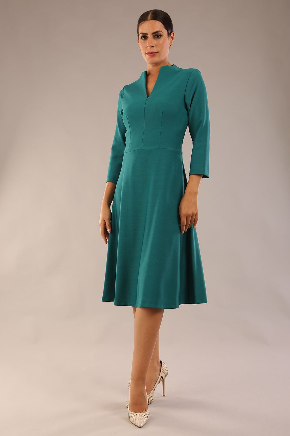 model is wearing diva catwalk palmerston vintage style a-line dress with sleeves and high neck with a slit in pacific green colour front