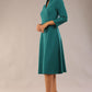 model is wearing diva catwalk palmerston vintage style a-line dress with sleeves and high neck with a slit in pacific green colour front