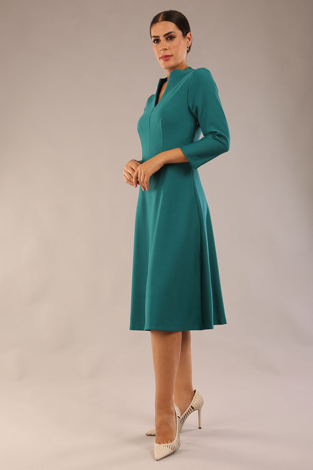 model is wearing diva catwalk palmerston vintage style a-line dress with sleeves and high neck with a slit in pacific green colour front