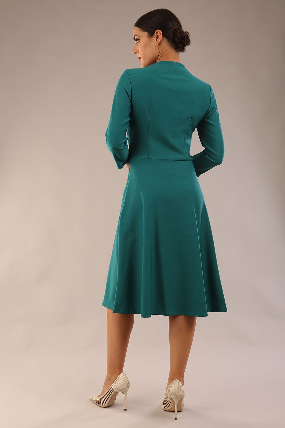 model is wearing diva catwalk palmerston vintage style a-line dress with sleeves and high neck with a slit in pacific green colour back