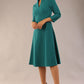 model is wearing diva catwalk palmerston vintage style a-line dress with sleeves and high neck with a slit in pacific green colour front