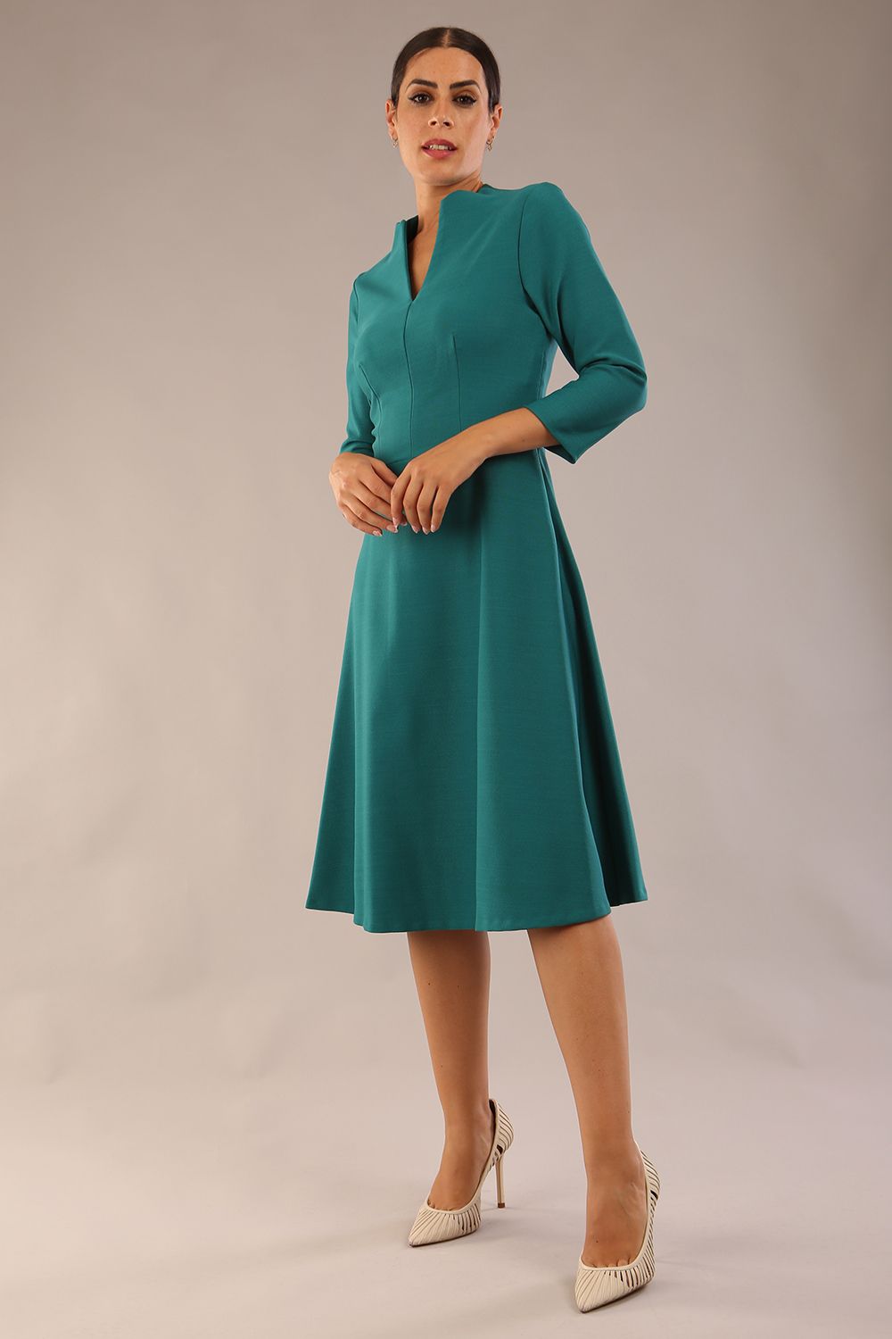 model is wearing diva catwalk palmerston vintage style a-line dress with sleeves and high neck with a slit in pacific green colour front