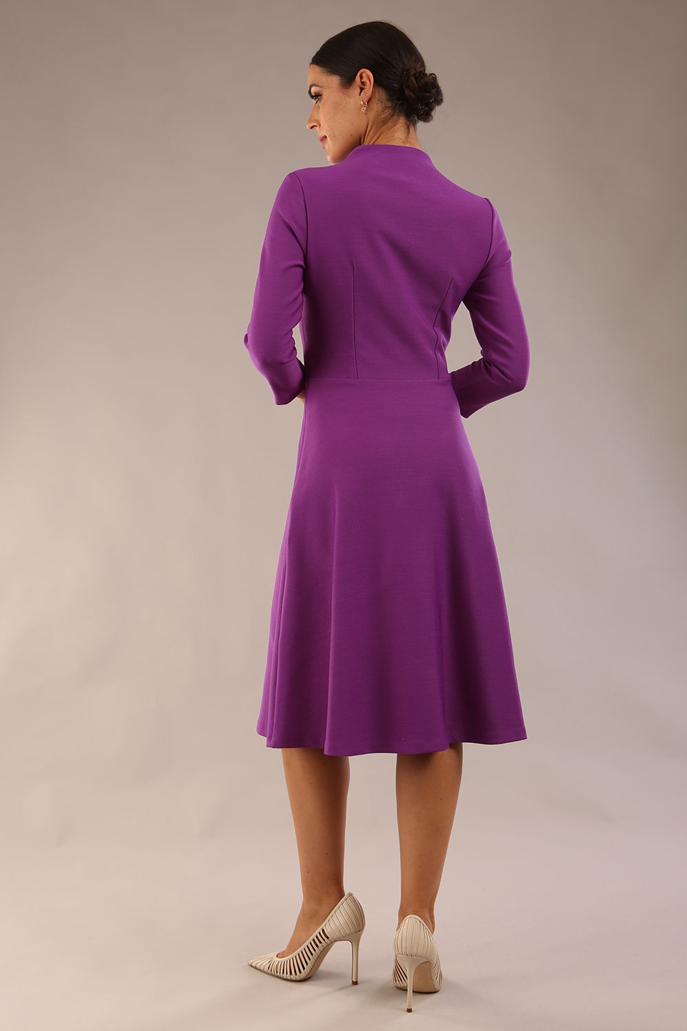 model is wearing diva catwalk palmerston vintage style a-line dress with sleeves and high neck with a slit in amethyst purple colour back