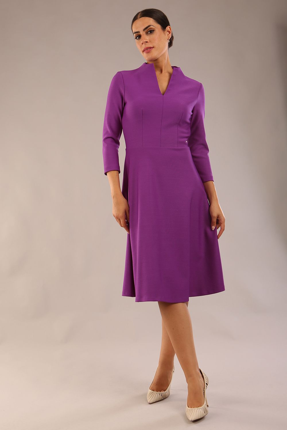 model is wearing diva catwalk palmerston vintage style a-line dress with sleeves and high neck with a slit in amethyst purple colour front