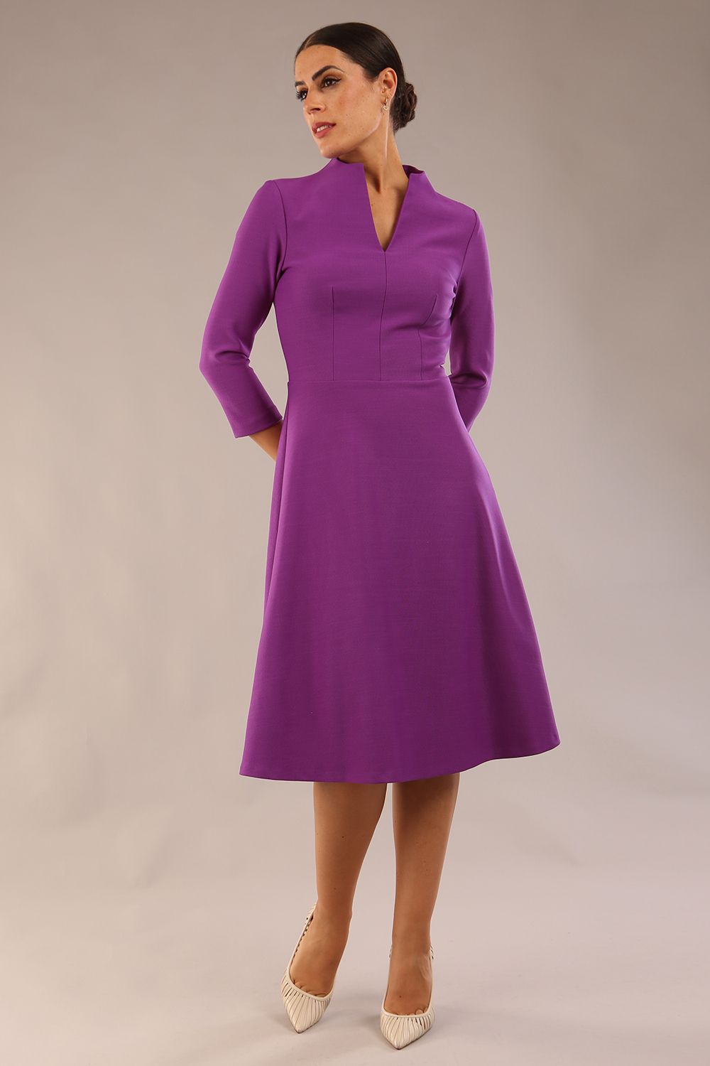 model is wearing diva catwalk palmerston vintage style a-line dress with sleeves and high neck with a slit in amethyst purple colour front