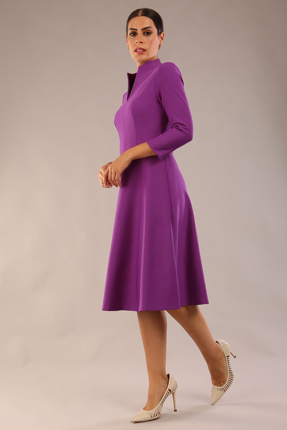 model is wearing diva catwalk palmerston vintage style a-line dress with sleeves and high neck with a slit in amethyst purple colour front