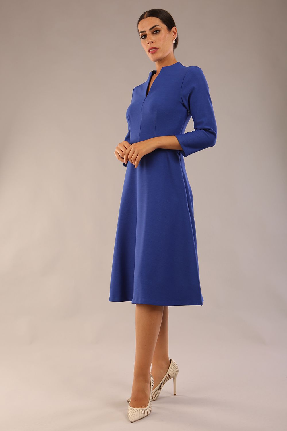 model is wearing diva catwalk palmerston vintage style a-line dress with sleeves and high neck with a slit in monaco blue colour front