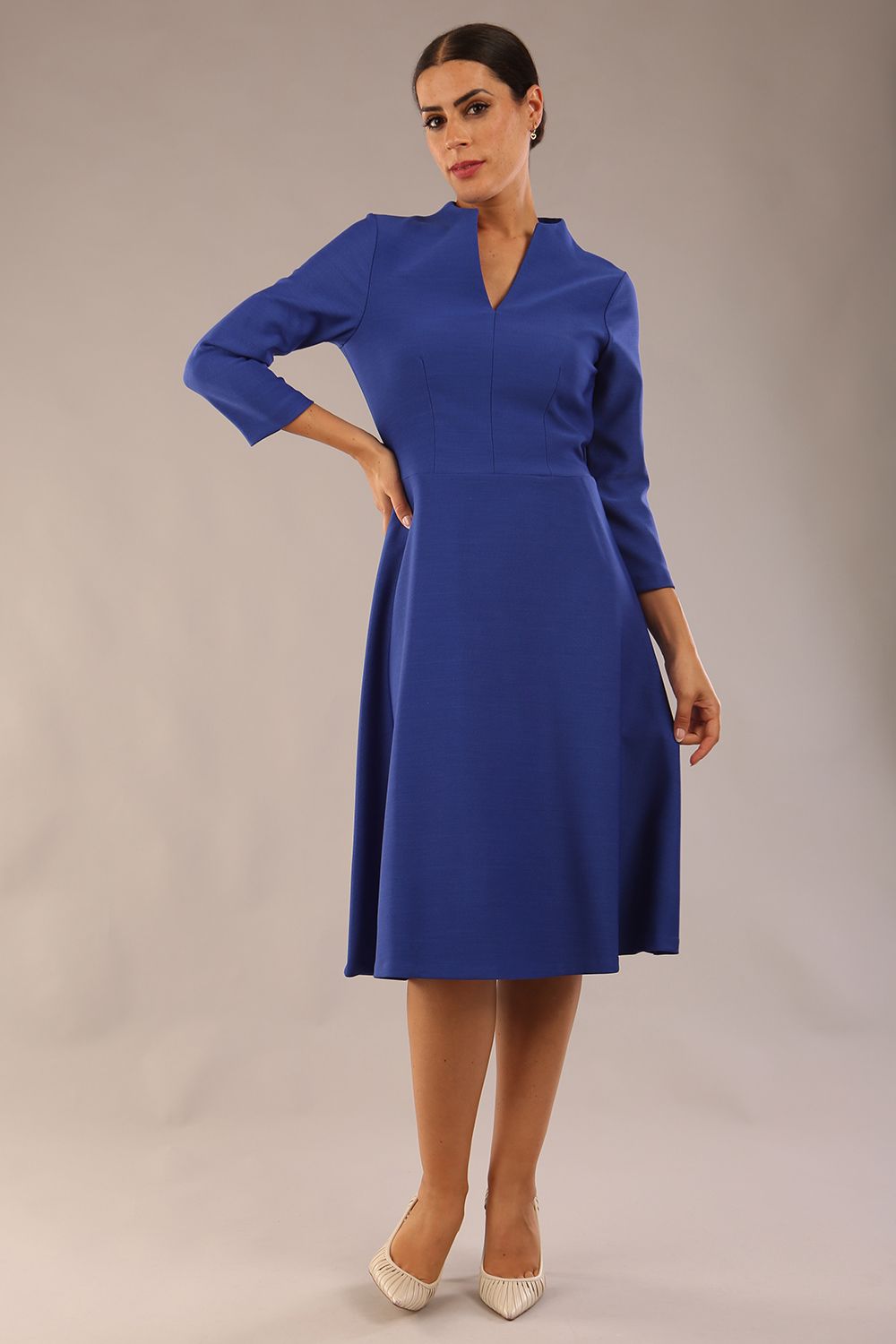 model is wearing diva catwalk palmerston vintage style a-line dress with sleeves and high neck with a slit in monaco blue colour front