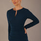 model wearing a diva catwalk lydia long sleeved pleated Mini Dress from Diva Catwalk in Teal in high heal shoes against a beige background close up