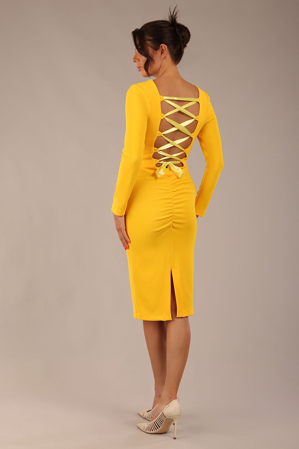 brunette model wearing a diva catwalk Zoey Sleeved Pencil Dress ribbon back with long sleeves and rushed details front and back in Sunshine Yellow colour back