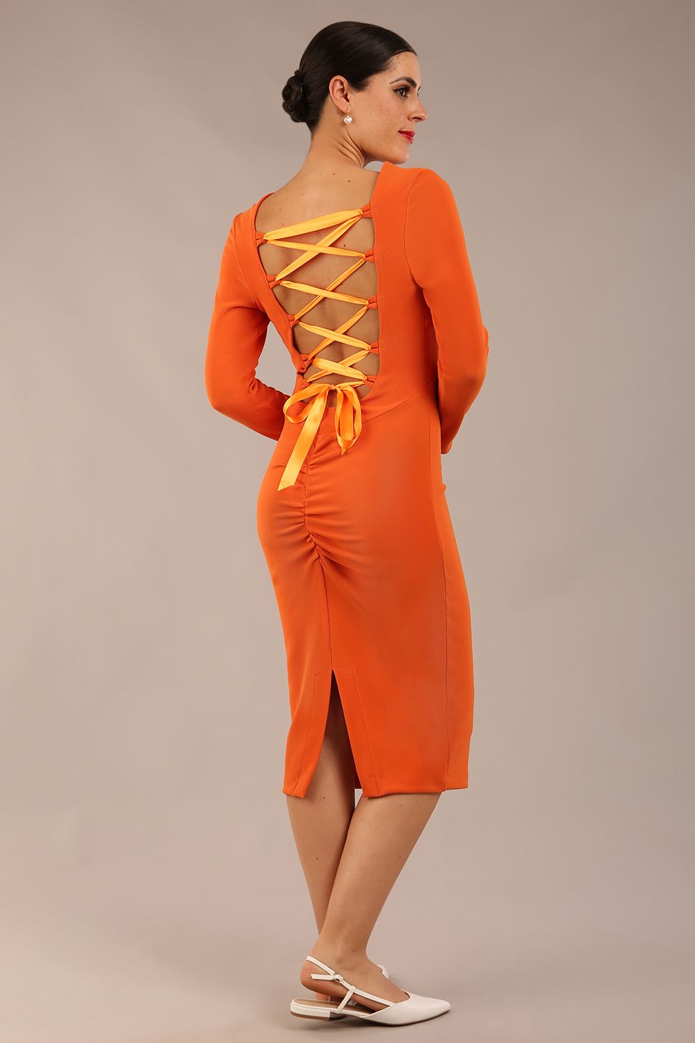 brunette model is wearing a diva catwalk Zoey Sleeved Pencil Dress ribbon back with long sleeves and rushed details front and back in Amber Orange colour back image