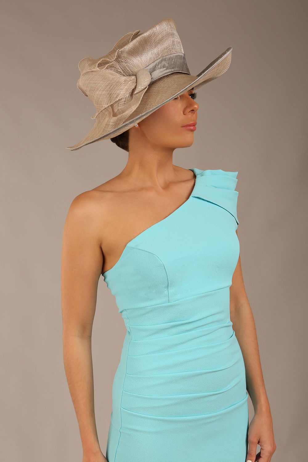 A Brunette Model is wearing a diva catwalk Phoebe One Shoulder Pencil Dress in knee length side vent - turquoise front close up with a hat