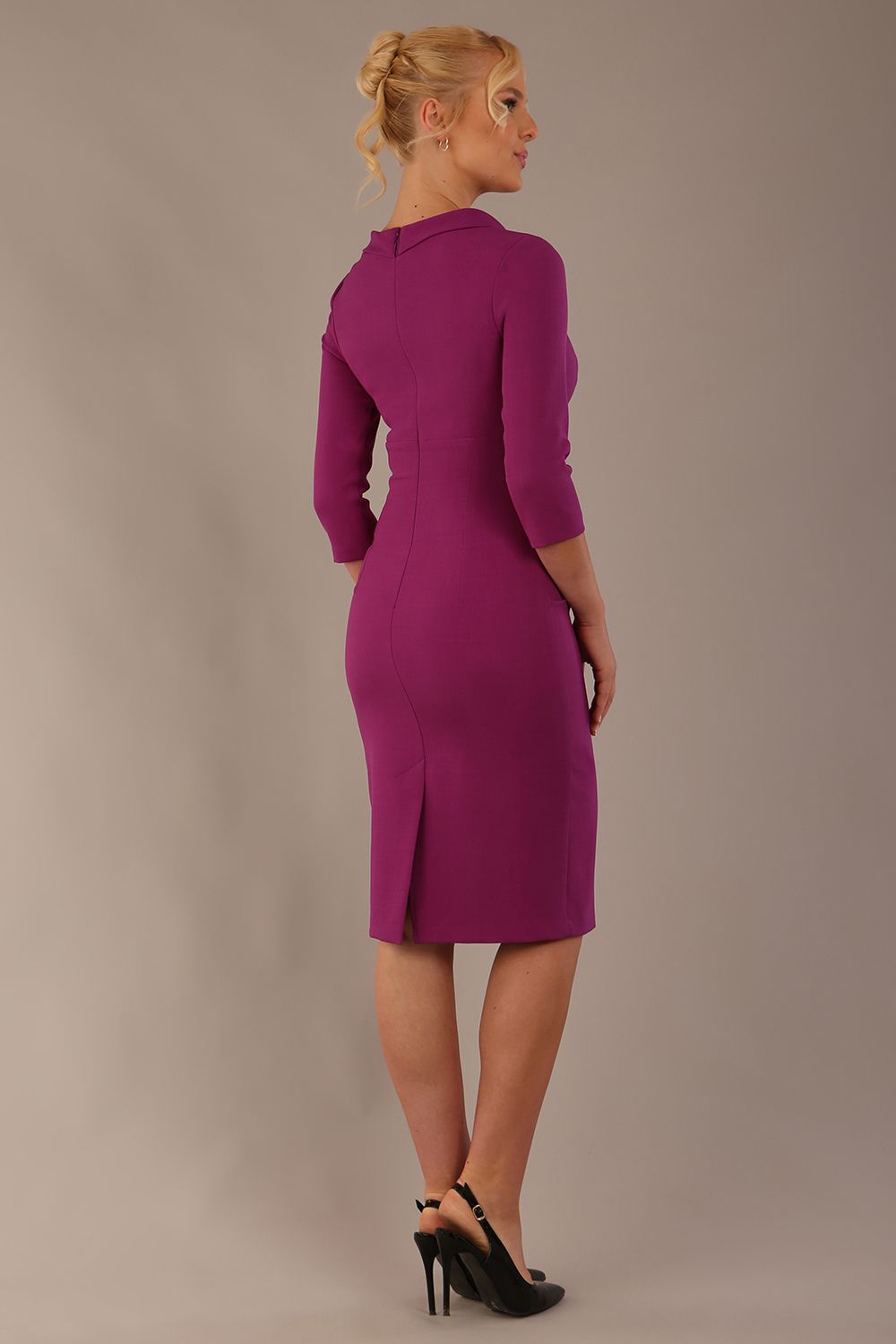 The model is wearing a diva catwalk Juliette 3/4 Sleeve Knee Length dress with bow detail in hollyhock purple colour against a plain background back view