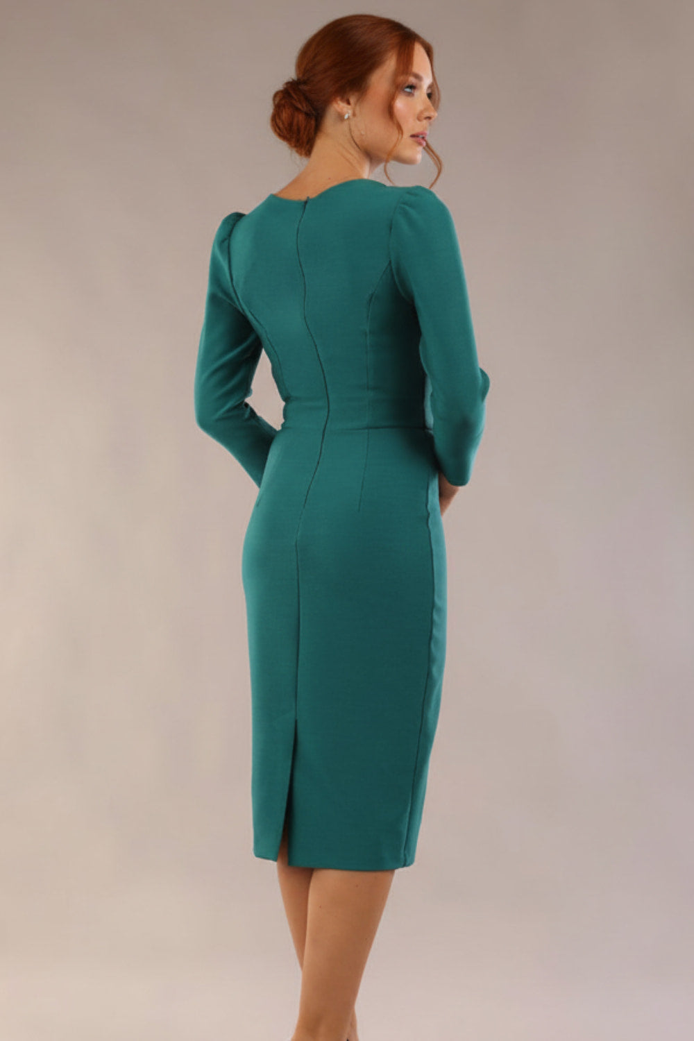Woman wearing a  SEED Cyrus pencil dress in pacific green, showing the tailored fit. against a beige background Back view (Pacific Green)