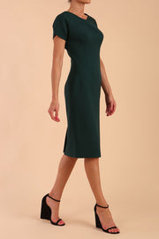 Model wearing a diva catwalk Sheena Short Sleeve with an open split Knee Length Pencil Dress with Diamond Neckline in Forest Green colour front side