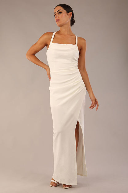 Model wearing Sabrina Maxi Dress with square neckline, sleeveless style, pleating details and side open split, open back in Ivory Cream