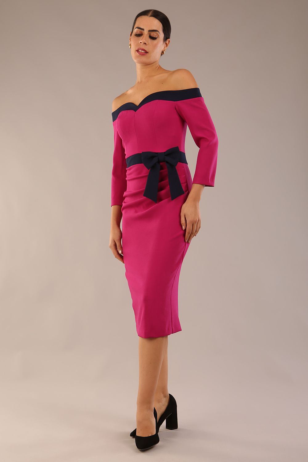 Model wearing a diva catwalk Brittany Off Shoulder Bow detail Pencil Dress with 3/4 sleeves and knee length in Magenta Haze and Navy Blue colour