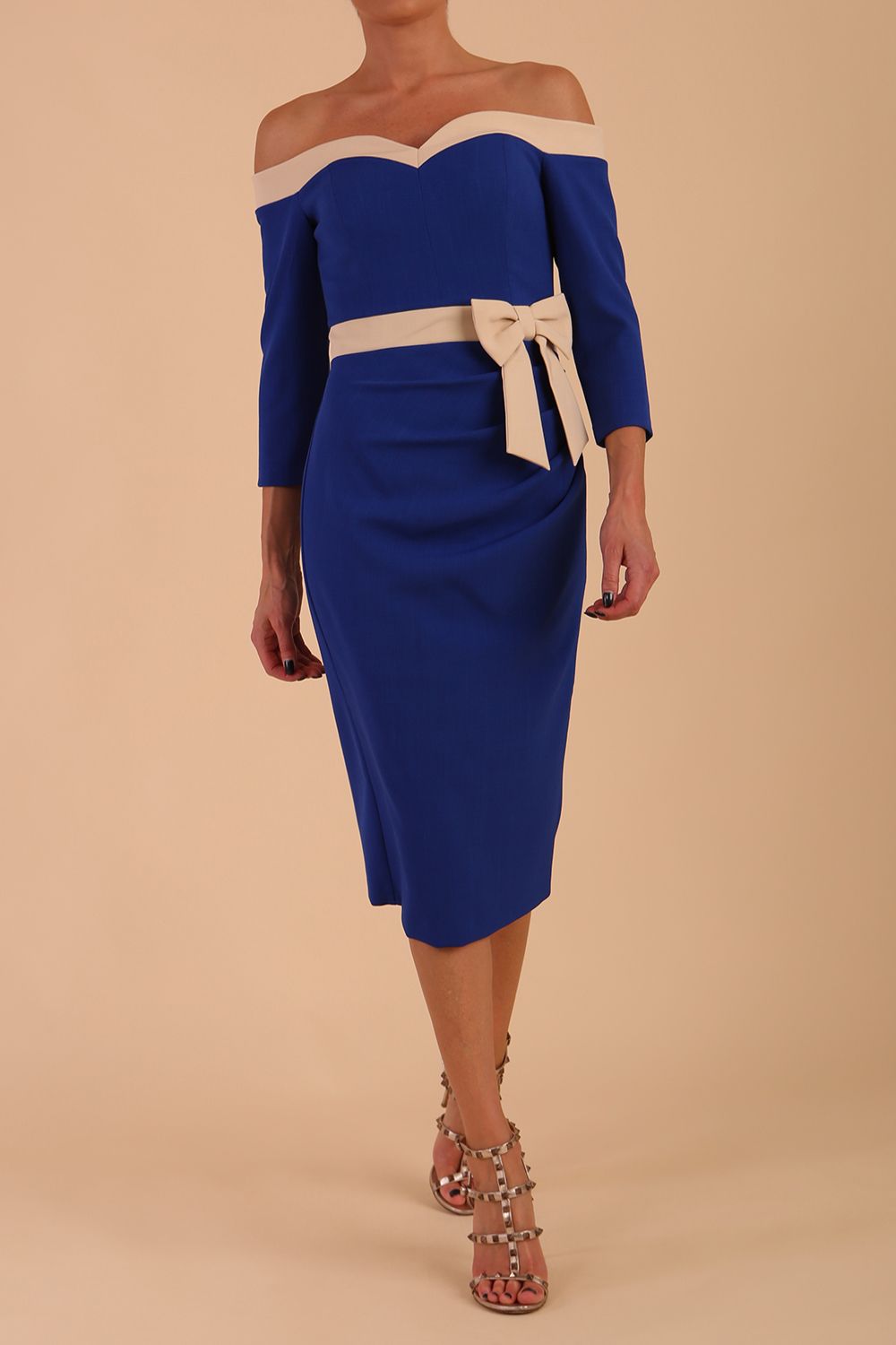 Model wearing a diva catwalk Brittany Off Shoulder Bow detail Pencil Dress with 3/4 sleeves and knee length in Cobalt Blue and Sandshell Beige colour front side detail