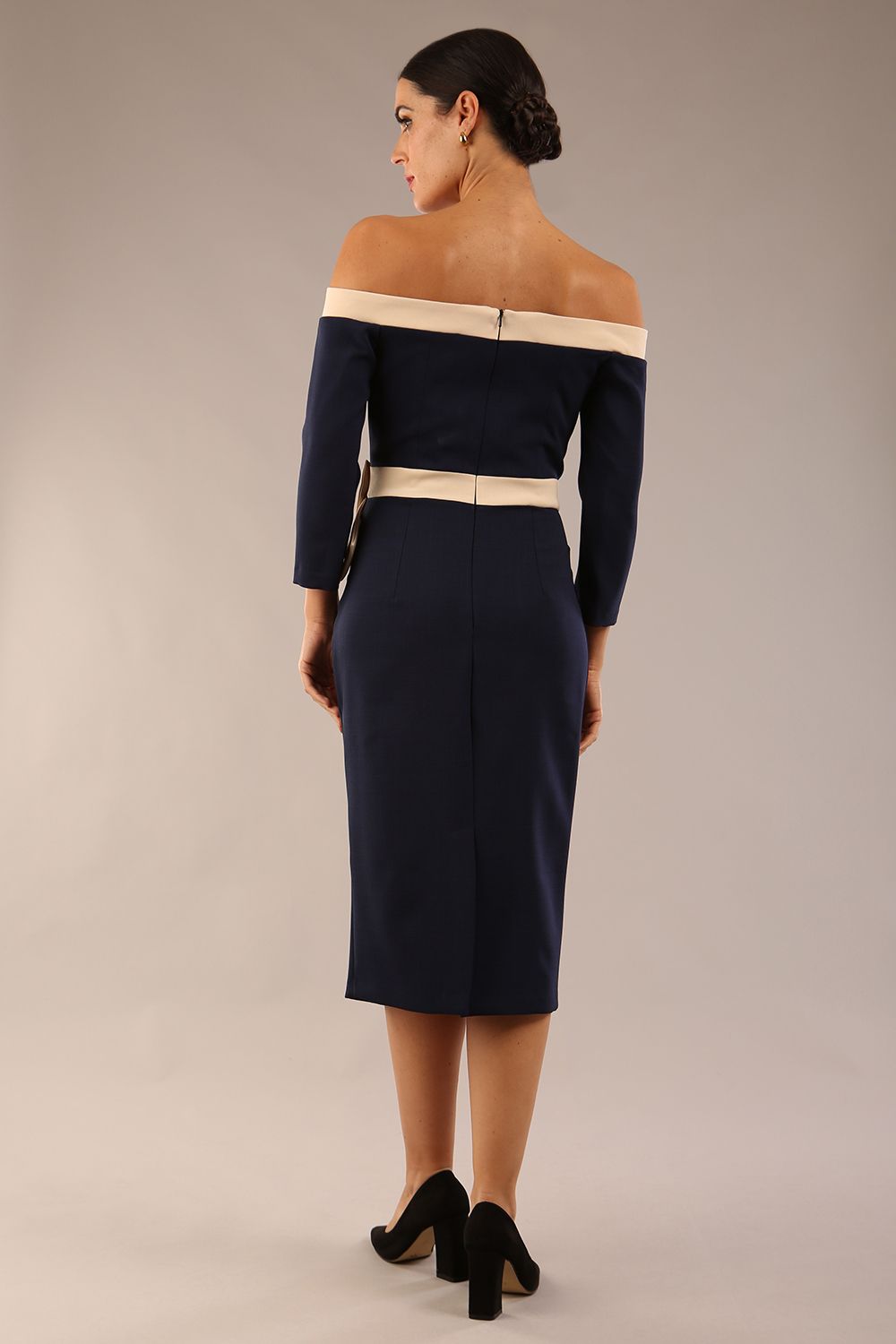 Model wearing a diva catwalk Brittany Off Shoulder Bow detail Pencil Dress with 3/4 sleeves and knee length in Navy Blue and Sandshell Beige colour front side